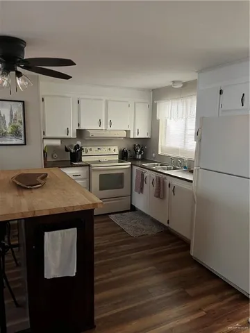 a kitchen with stainless steel appliances granite countertop a stove a refrigerator a sink dishwasher and white countertops with wooden floor