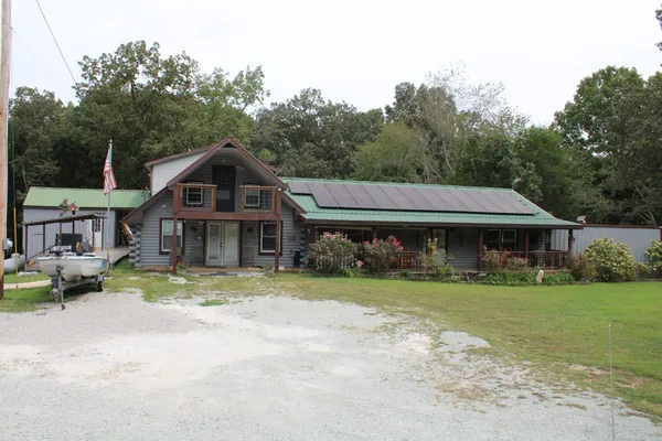 a view of a house with a yard and large tree