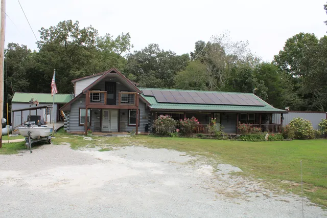 a view of a house with a yard and large tree
