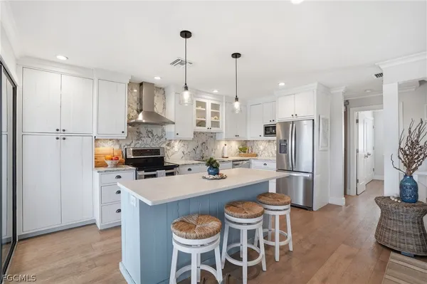 a kitchen with stainless steel appliances kitchen island a table chairs refrigerator and sink