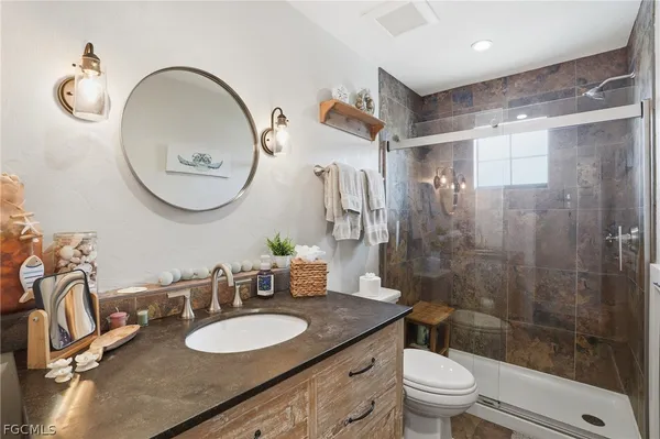 a bathroom with a granite countertop sink mirror toilet and shower