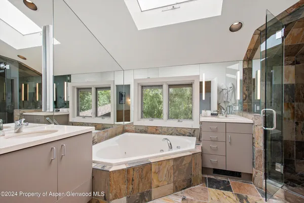 a bathroom with a granite countertop tub sink and mirror