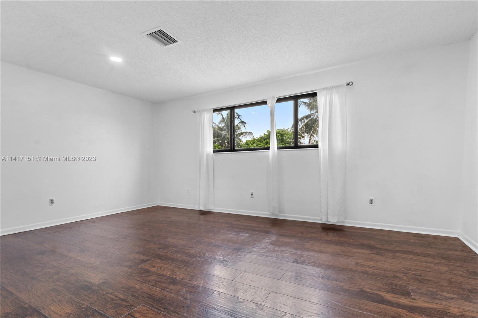 9435 Southwest 151st Avenue Miami, FL 33196 - Photo 10 of 35 a view of an empty room with wooden floor and a window