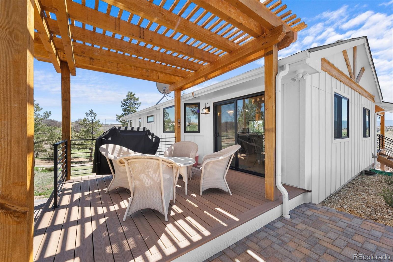 3303 West Wolfensberger Road Sedalia, CO 80135 - Photo 32 of 36 a view of a patio with table and chairs and wooden floor