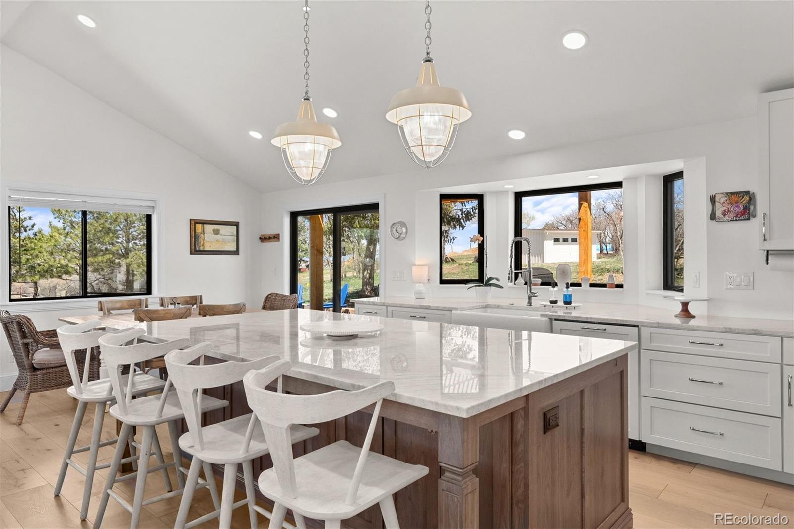 3303 West Wolfensberger Road Sedalia, CO 80135 - Photo 9 of 36 a large kitchen with a center island table and chairs in it