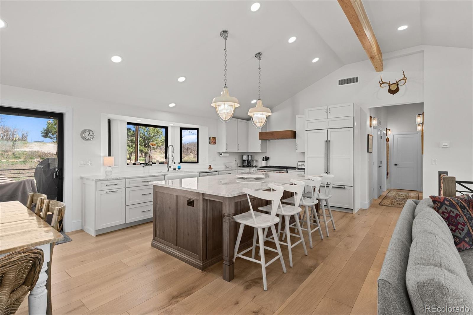 3303 West Wolfensberger Road Sedalia, CO 80135 - Photo 10 of 36 a kitchen with a dining table chairs wooden floor cabinets and appliances