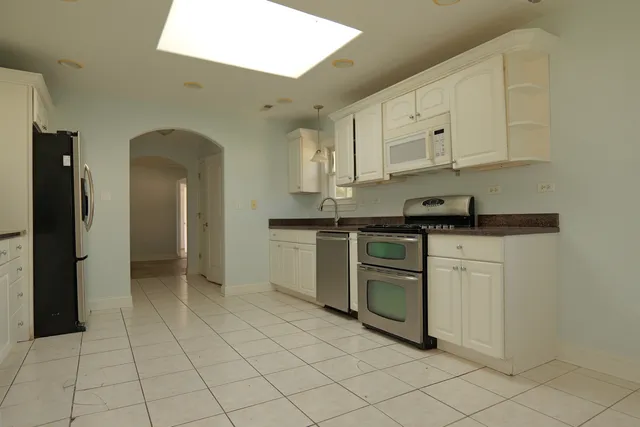a kitchen with white cabinets a sink and appliances