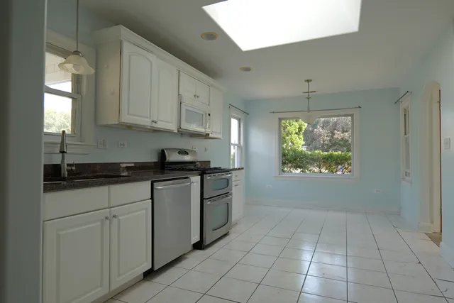a kitchen with stainless steel appliances granite countertop a stove a sink and a white cabinets