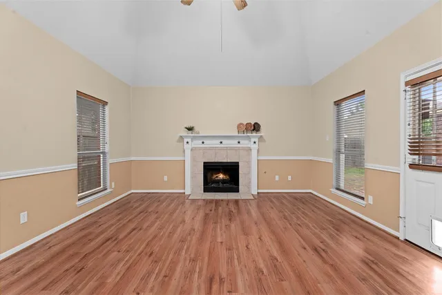 a view of an empty room with wooden floor fireplace and a window
