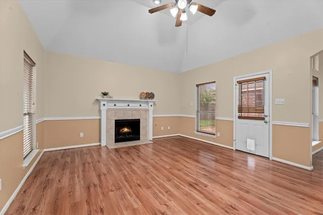 a view of a livingroom with wooden floor a fireplace and windows