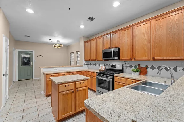 a kitchen with stainless steel appliances granite countertop a stove top oven a sink dishwasher and a microwave oven on the blue kitchen countertops