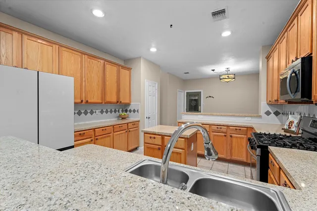 a kitchen with stainless steel appliances granite countertop a sink a stove and a refrigerator
