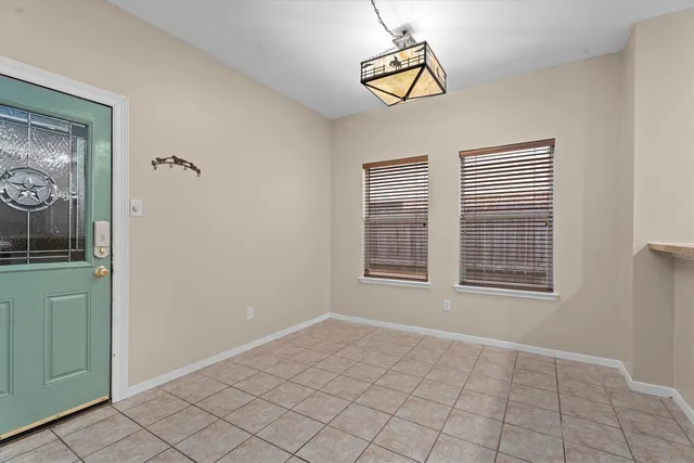a view of an empty room with window and chandelier fan