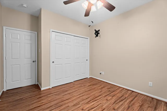 an empty room with wooden floor chandelier fan and closet area