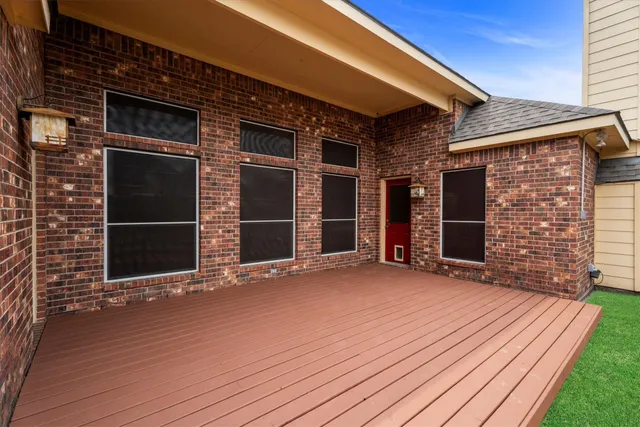 a view of an empty room with wooden floor and a brick wall