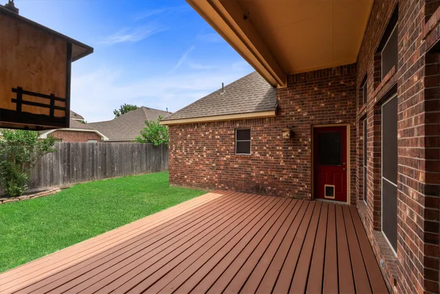 a view of a backyard with wooden floor and fence