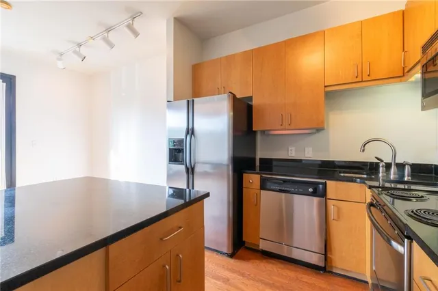 a kitchen with stainless steel appliances granite countertop a sink a stove and a refrigerator