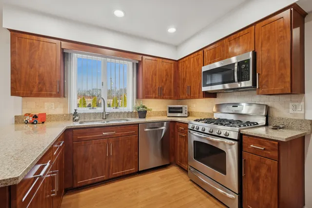 a kitchen with stainless steel appliances granite countertop wooden cabinets stove top oven and sink