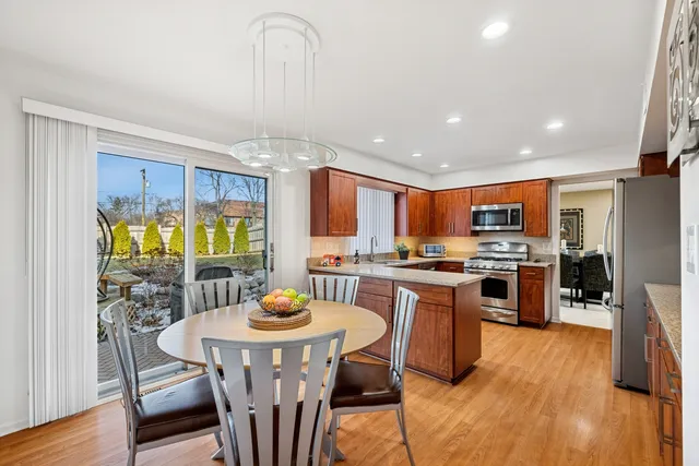 a kitchen with stainless steel appliances a dining table chairs stove and refrigerator