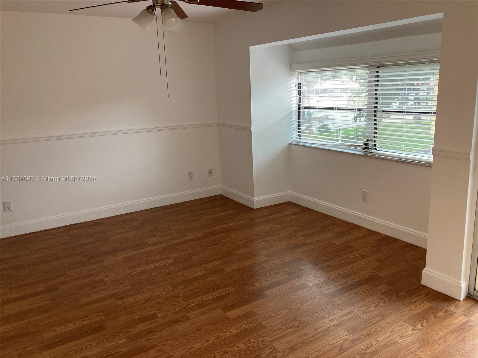 13731 Southwest 84th Street, Unit E Miami, FL 33143 - Photo 5 of 19 an empty room with wooden floor and windows