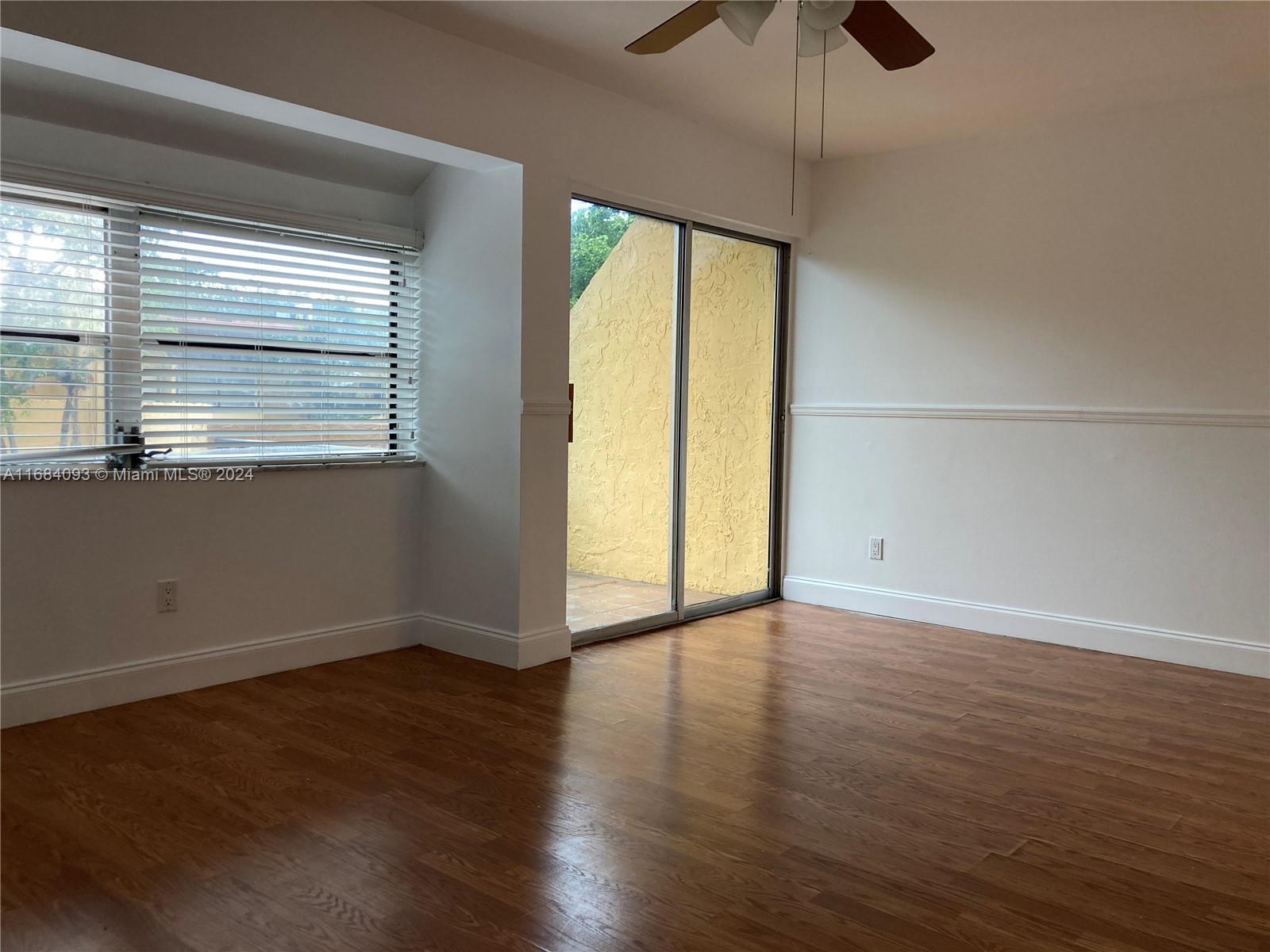13731 Southwest 84th Street, Unit E Miami, FL 33143 - Photo 6 of 19 an empty room with wooden floor and windows