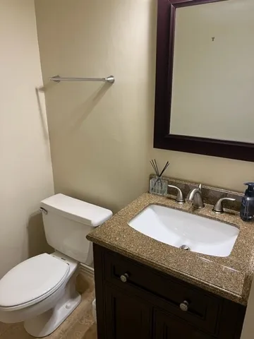 a bathroom with a granite countertop toilet sink and mirror