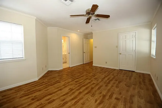 a view of empty room with wooden floor and fan