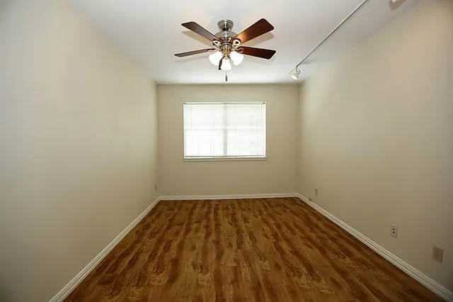 an empty room with a window and a fan