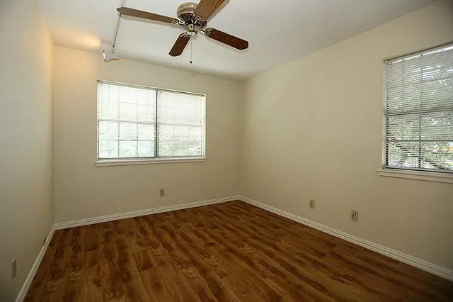a view of a room with wooden floor fan and windows