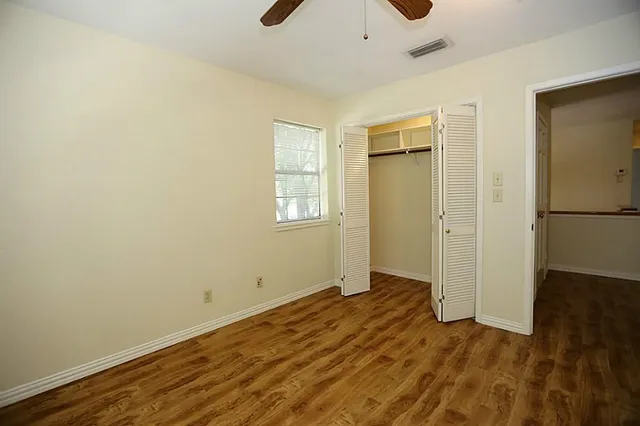 an empty room with wooden floor and windows