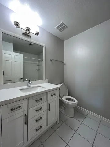 a bathroom with a granite countertop sink a toilet and a mirror