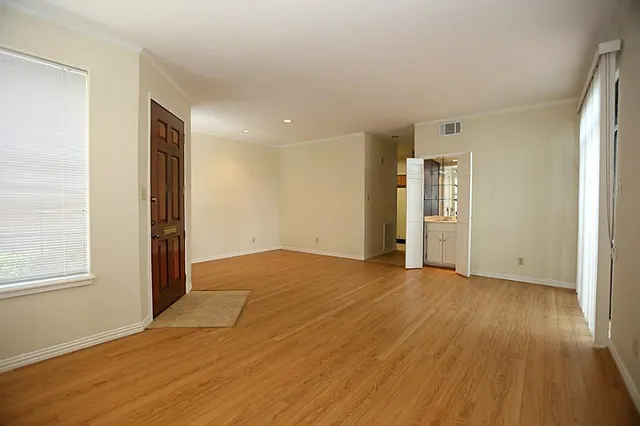 an empty room with wooden floor and windows