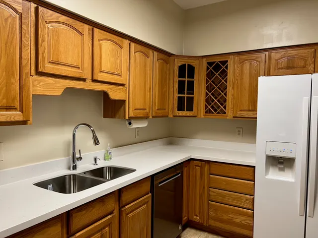 a kitchen with stainless steel appliances granite countertop a sink and a refrigerator with wooden cabinets
