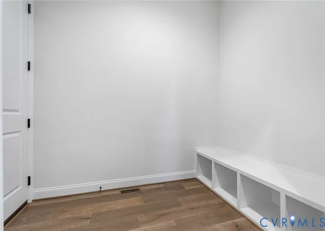 an empty room with wooden floor chandelier and windows