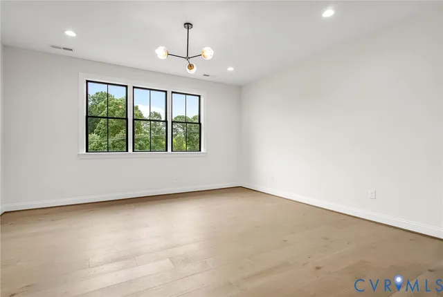 a view of an empty room with a window and wooden floor