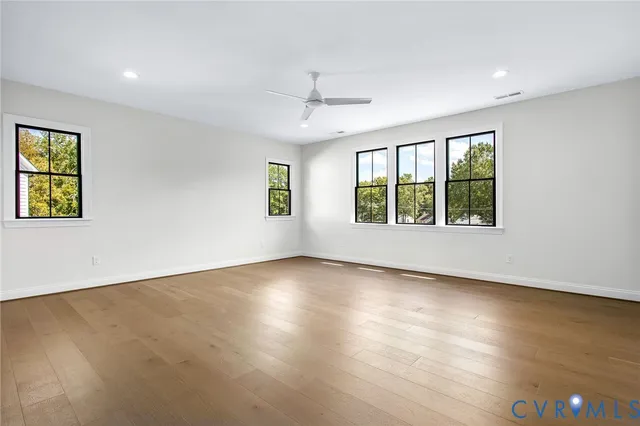 an empty room with wooden floor and natural light
