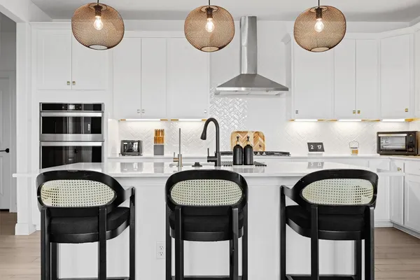 a kitchen with stainless steel appliances granite countertop a sink a stove a dining table and chairs