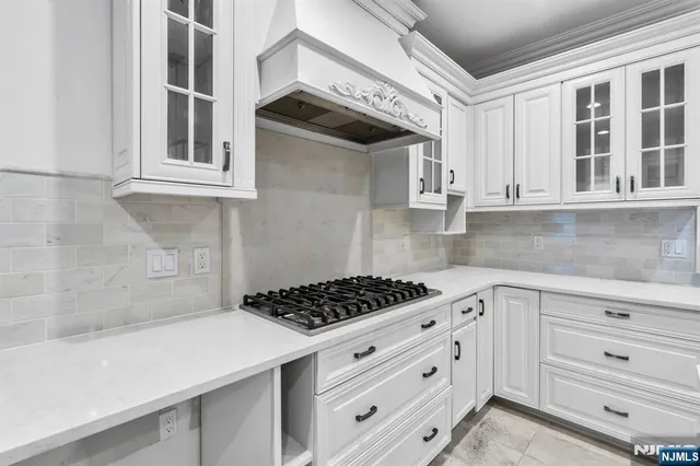 a kitchen with white cabinets and stove