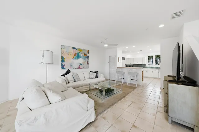 a living room with furniture a flat screen tv and kitchen view