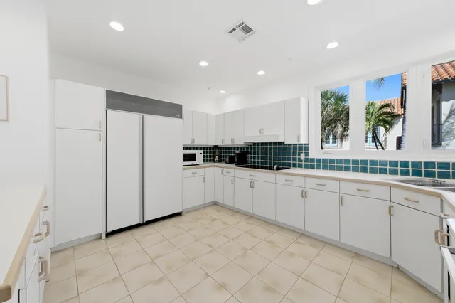 a large white kitchen with granite countertop a large counter top space appliances and cabinets