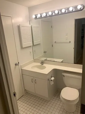a bathroom with a granite countertop toilet sink and mirror