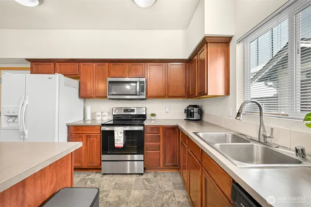 a kitchen with stainless steel appliances granite countertop a sink stove microwave and refrigerator