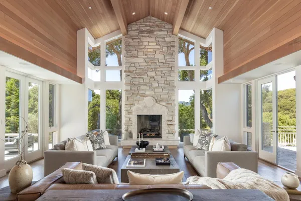 a living room with furniture fireplace and large windows