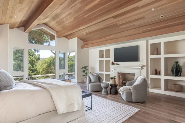a bedroom with furniture a flat screen tv and a fireplace