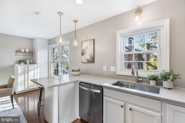 a kitchen with granite countertop a refrigerator a stove a dining table and chairs with wooden floor