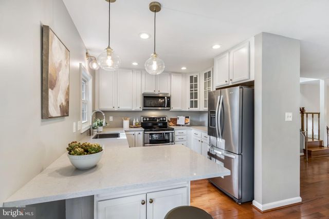 a kitchen with refrigerator a microwave and chairs