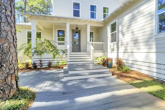 a view of a house with potted plants and a bench in front of it