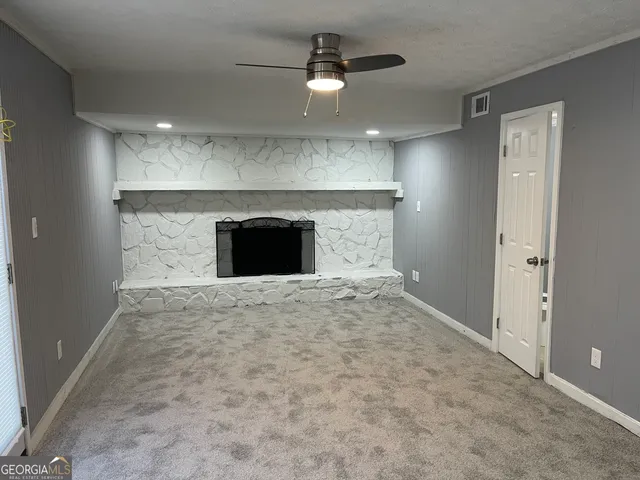an empty room with a fireplace and a ceiling fan