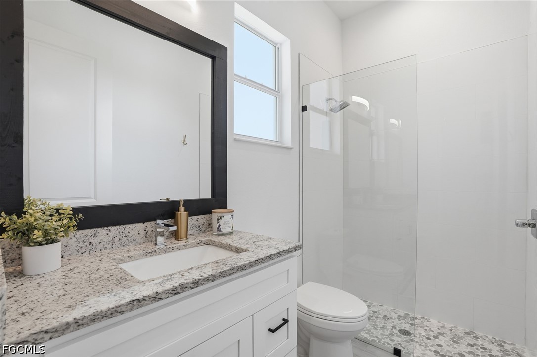 4635 Northwest 32nd Street Cape Coral, FL 33993 - Photo 17 of 30 a bathroom with a granite countertop sink a toilet and a mirror