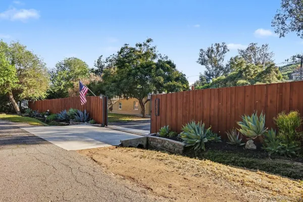 a backyard of a house with plants and trees with wooden fence